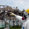 man in hazmat suit pointing to damaged Fukushima reactor