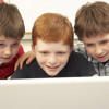 Three school-age boys looking at a laptop computer/Monkey Business Images, Shutterstock