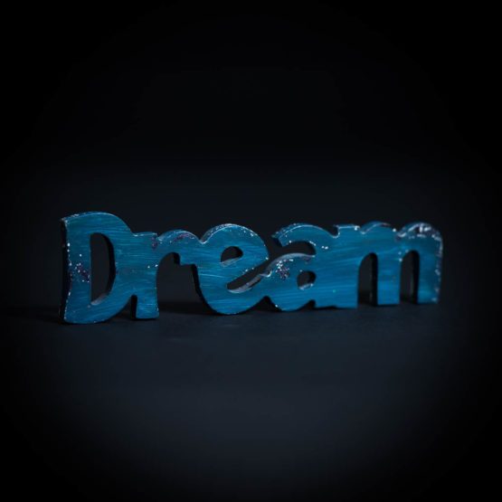 Wood cutout, painted blue, spelling the word "Dream"