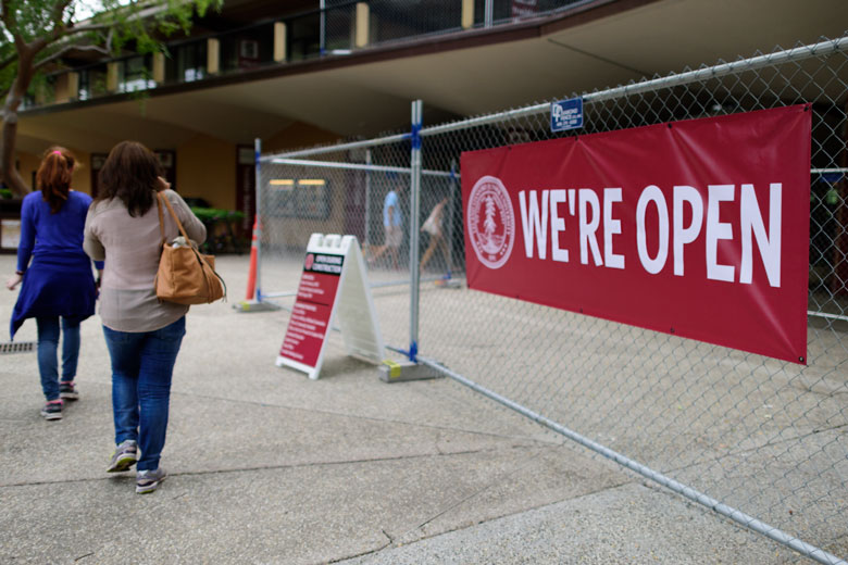 construction fence at Tresidder Memorial Union with 'We're Open' banner