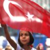 A Turkish girl wearing a headband bearing the name of Turkish president Recep Tayyip Erdogan waves her nation flags during a pro-government demonstration in front of the old parliament building, in Ankara, Turkey, Wednesday, July 20, 2016. The coup has led to public anger and calls for the government to reinstate capital punishment, while the state-run religious affairs body declared no religious rites would be performed for the coup plotters killed in the uprising