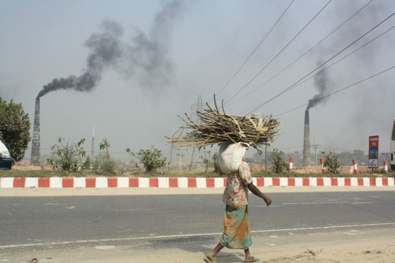 Woman walking past smoke in Bangladesh