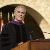 Marc Tessier-Lavigne at the podium with flags and arches in the Main Quad in the background.