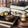 Wood gavel, bunch of keys, scales and stack of old books against the background of a row of antique books bound in leather