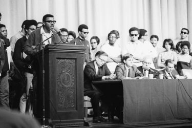 Members of the Black Student Union take the stage and microphone during a program following the assassination of Martin Luther King, Jr., April 8, 1968