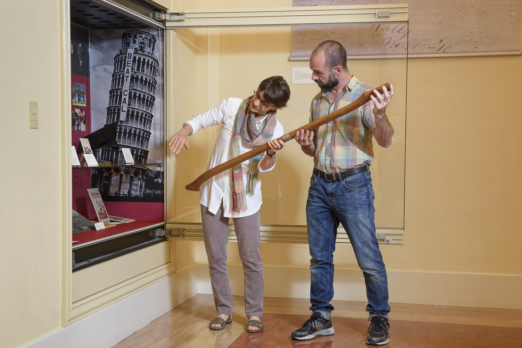 Exhibition designer Becky Fischbach and archivist Daniel Hartwig placing handle of Stanford Axe in display case at Green Library