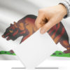 ballot being inserted into box with California flag in background