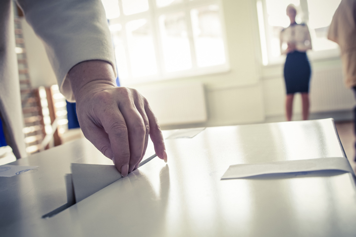 Hand of a person casting a ballot at a polling station during voting