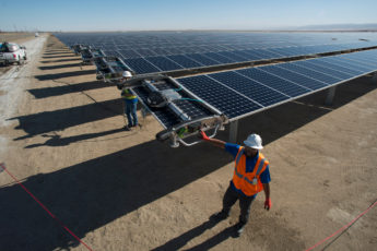 Workers starting a robot on a solar panel.