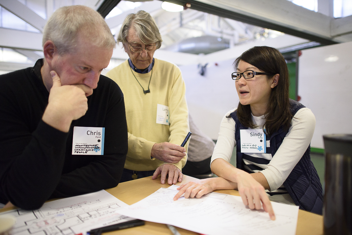 Chris Ford, Larry Leifer and Sindy Tang around a desk working on an exercises in the Catalyst workshop.