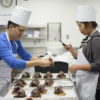 student garnishing wood pigeon while classmate takes photo