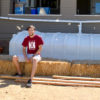 Student Andrew Jacobs sits on a water catchment system behind a house