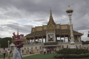 people on a lawn and sidewalk in front of an ornate palace