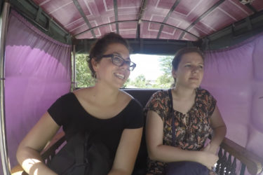 two woman seated in a narrow carriage covered with fabric