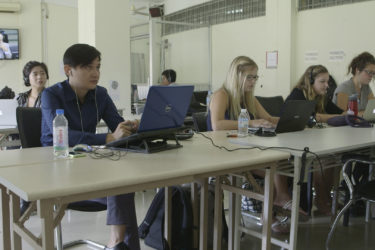 people working on laptops as they observe a televised trial