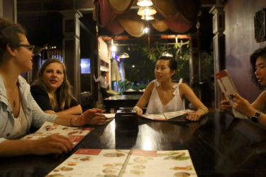 four women looking at menus, seated around a table in a restaurant