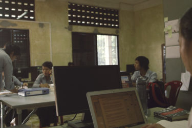 people seated around two tables, one working on a laptop