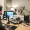 Michael Osborne, audio production director in a sound studio with students Megan Shea and Isha Salian practicing interview skills