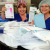 Medical Center personnel wearing hair nets hold paperwork.