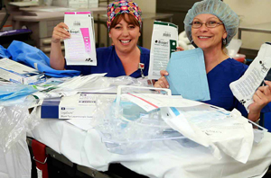 Medical Center personnel wearing hair nets hold paperwork.