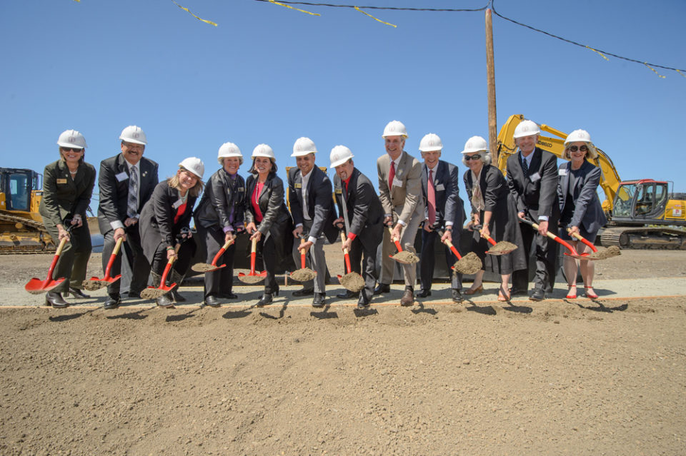 A group in hardhats holding shovels.