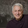 portrait of Andre Linde, professor of physics, in front of a blackboard of equations