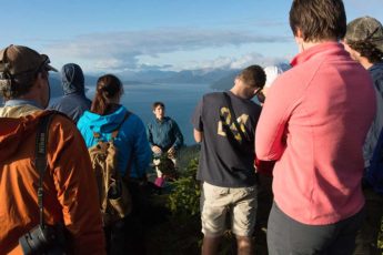 Instructor Zach Brown talking to students at the water's edge in rural Alaska