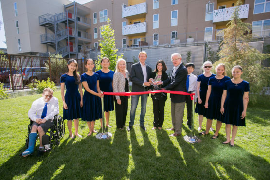 A group of children and adults cutting a ribbon