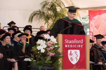 At lectern at graduation ceremony, Augustus White urged the graduates to help mend the nation's health care system.