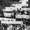 Students holding protest signs at a football game