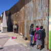 people at a gate at the Mexico-US border