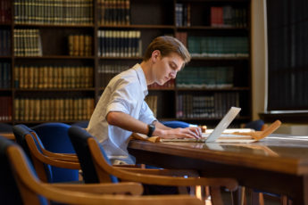 Undergraduate Anatole Schneider examing Italian newspapers from 1947-48 at the Hoover Library reading room.