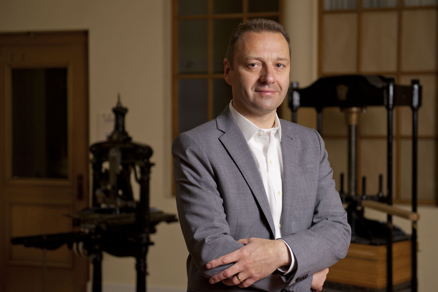 portrait of Alan Harvey, director of Stanford University Press, with old hand-operated printing presses in background