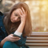 young woman on a bench looking at her cell phone