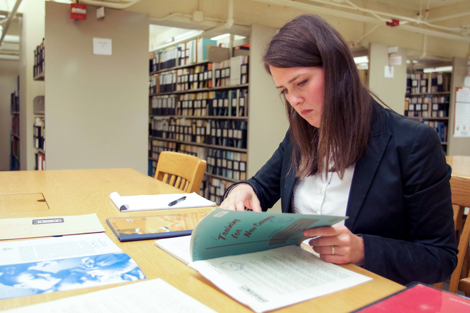 Claire Dunning in the library examining old government training manual