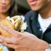 Happy man (African American) in a fast food restaurant eating a hamburger with his girlfriend