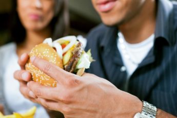 Happy man (African American) in a fast food restaurant eating a hamburger with his girlfriend