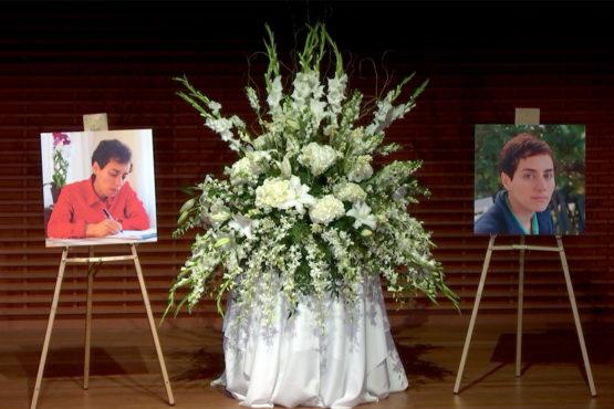 Two large photos of Maryam Mirzakhani with a flower arrangement on stage. 