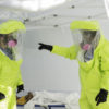 doctors in hazard suits in a medical tent with a boy on a cot