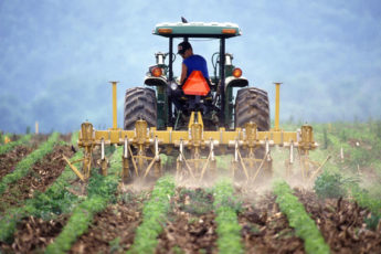 a farmer on a tractor tilling soil