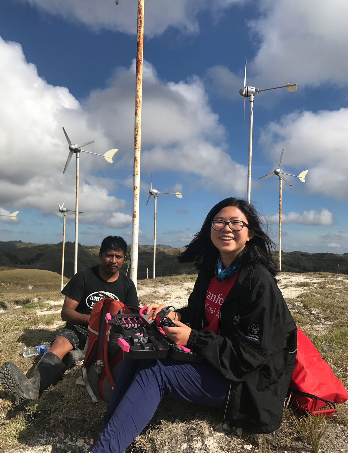 In 2017, Celine Wang, a Stanford undergraduate, helped create and install affordable remote monitoring systems for small-scale power plants on the Indonesian island of Sumba, under an Engineering in Service International Fellowship awarded by the university. She is pictured at the Palindi Wind Turbine farm with Mas Petu, a supervisor with IBEKA, the Indonesian non-governmental organization devoted to improving the living standards of rural communities – including through electrification projects using renewable energy.