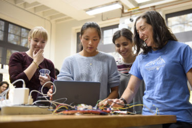 Grad student Laura Blumenschein, left, observes Grace Zhao and Goli Emami's project which gives haptic feedback while navigating a maze. Cara Welker, right, a grad student in bioengineering tests the device.