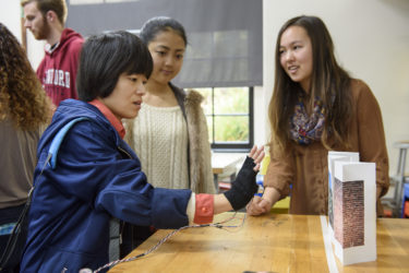 Visiting scholar, Rui Yang, tests the depth sensing glove developed by freshmen Megumi Sano and Kira Jan.