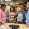 Senior Moses Swai, left, gets a demonstration from Jabreea Johnson, Charlotte Peale, and Johnny Armenta who developed a Foot Haptic device.