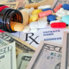 prescription bottle with pills spilling out over scrip and money