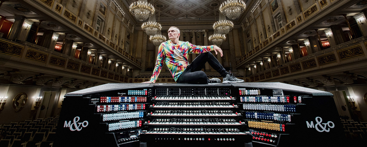 Cameron Carpenter sitting atop an organ