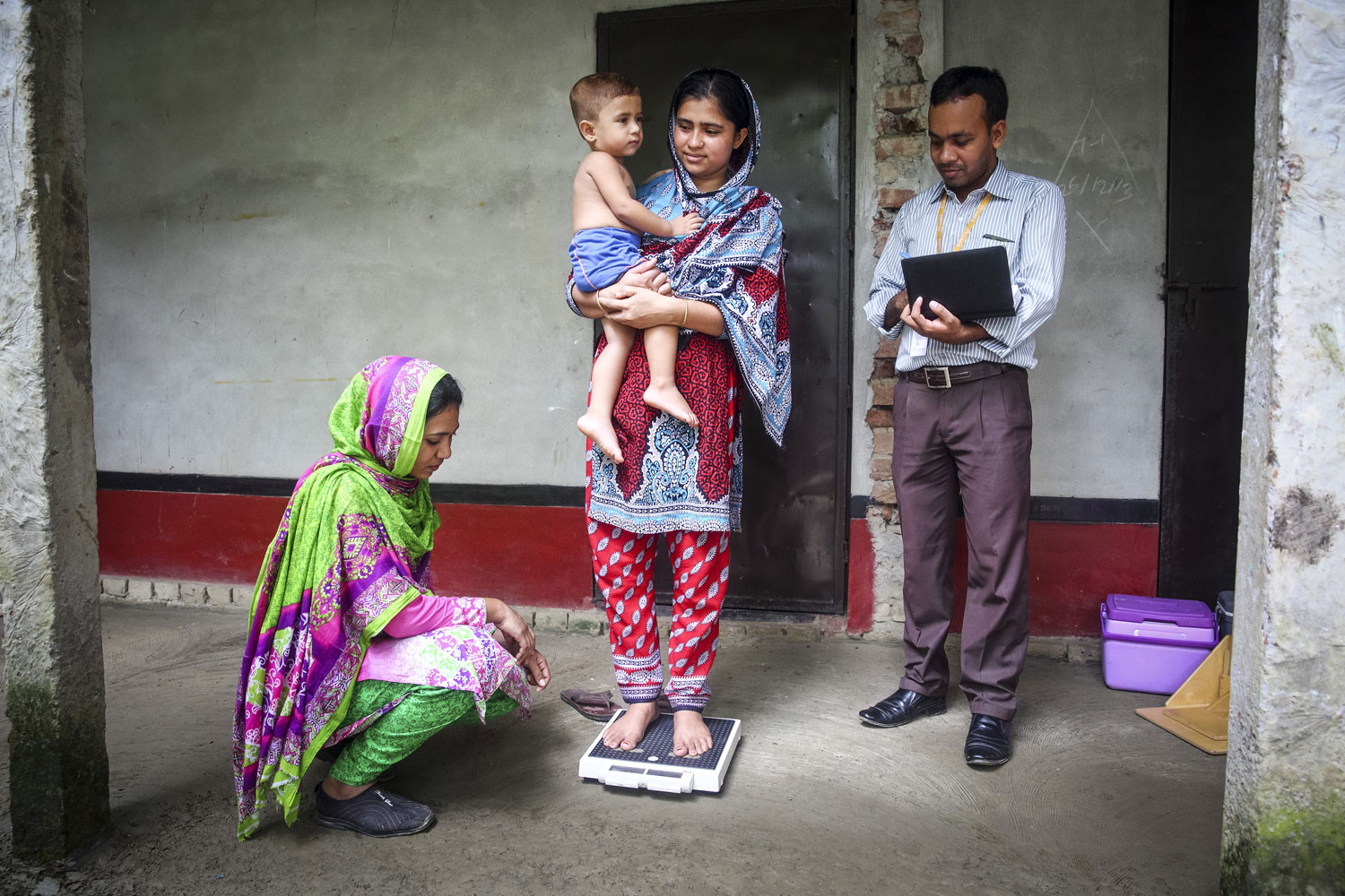 Study data collectors measure a child's growth in Dhaka, Bangladesh, to assess impact of water, sanitation and hygiene interventions.