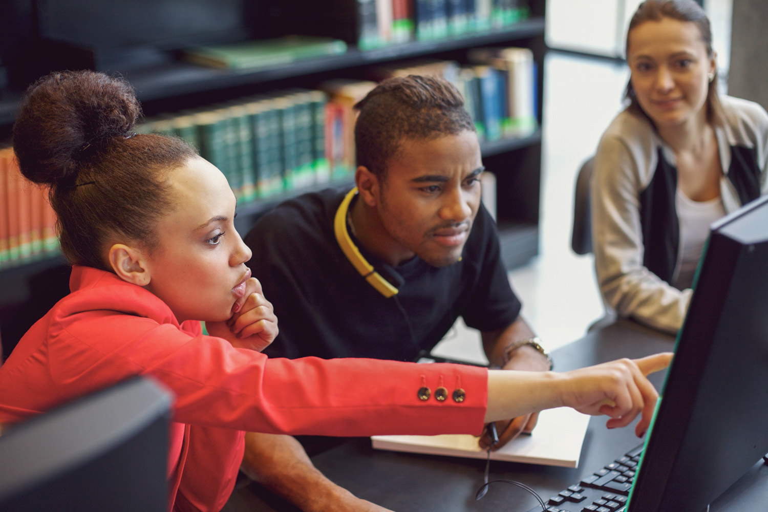 Small group of students working on computer in a library.