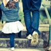 Child holding parents' hands going up stairs