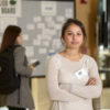 Emily Shaw standing with her arms crossed in front of a job board